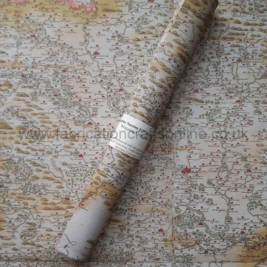 A roll of paper printed with a copy of a hand printed and hand painted map in greens, browns, and yellows, with towns painted red lying on top of an open sheet of the same paper.