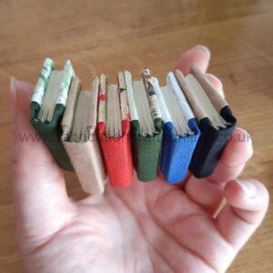 A hand holding a selection of miniature handmade books.