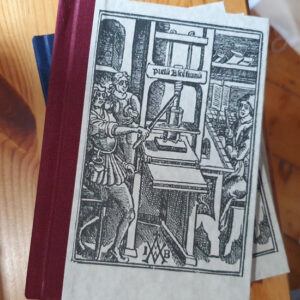 A hardback book with bookcloth spine and paper cover with a black and white medieval image of a printing press surrounded by printers.