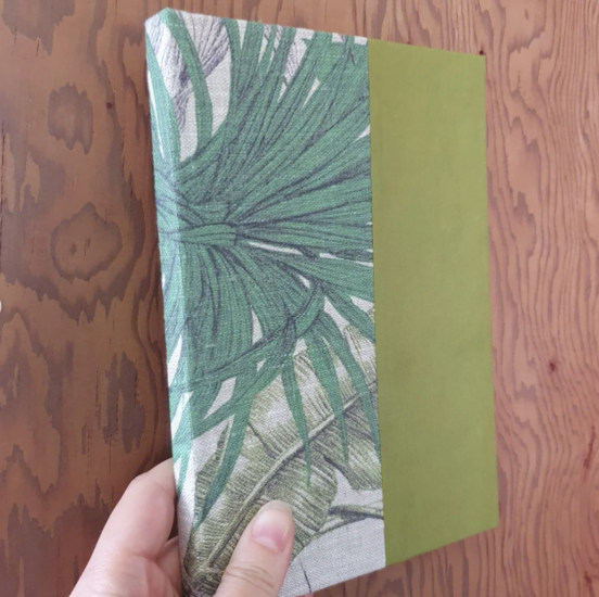 An A5ish hardback notebook with patterned fabric on the spine and paper in a complimentary colour on the covers.
