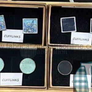Assorted cufflinks displayed in four open boxes: top row has two blue patterned square cufflinks, top row right has two dark square cufflinks, bottom row left shows two mint-green round cufflinks, bottom row right has a single dark cufflink.