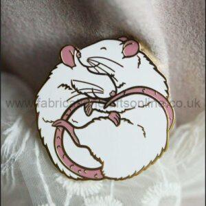 An enamel pin badge featuring two hugging white pet rats