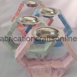 Pastel-painted interlocking geometric wooden sculpture with four shallow metal bowls on top.