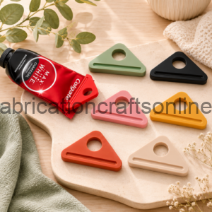 Flat lay of a red paint tube and six pastel triangle-shaped plastic handles arranged on a light wooden board, with a plant and towel in the background.
