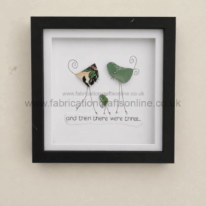 Framed mixed-media artwork of three bird figures made from metal shapes and wire, with the caption 'and then there were three...'