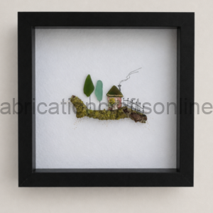 Miniature landscape inside a black square frame: mossy hill, three trees, a small house with a fence.