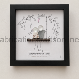 Framed decorative artwork: a twig shelf holds two small ceramic figures beneath hand-drawn vines with the caption 'somewhere only we know'.