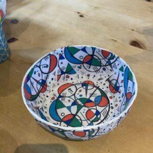 Colorful abstract-patterned paper bowl on a wooden table edge visible in the foreground.