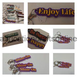 Collage of colorful silicone keychains with phrases like 'Shine On' attached to metal keyrings.