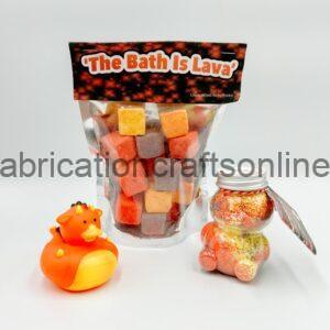 Bag of colorful lava bath rocks labeled 'The Bath Is Lava' with an orange rubber duck and a bear-shaped jar of bath beads nearby.