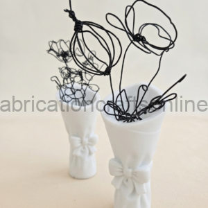 Two white ceramic vases with bow decorations holding tangled black wire sculptures.