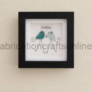 Framed illustration of two whimsical birds labeled 'besties' on a beige wall. A black frame with a white mat surrounds the artwork.