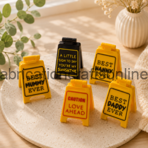 Five yellow plaques with bold black messages arranged on a round beige platter: 'Best Mommy Ever', 'Best Nanny Ever', 'Best Daddy Ever', 'Caution Love Ahead', and 'A Little Sign to Say You're My Sunshine'