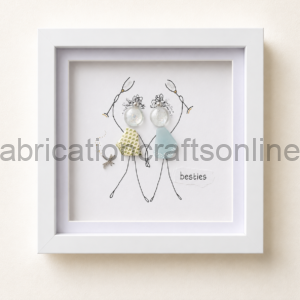 Framed illustration of two stick-figure friends holding hands, wearing fabric dresses, with decorative earrings and a star charm, captioned “besties”