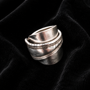 Silver stackable ring with multiple bands resting on black velvet fabric.