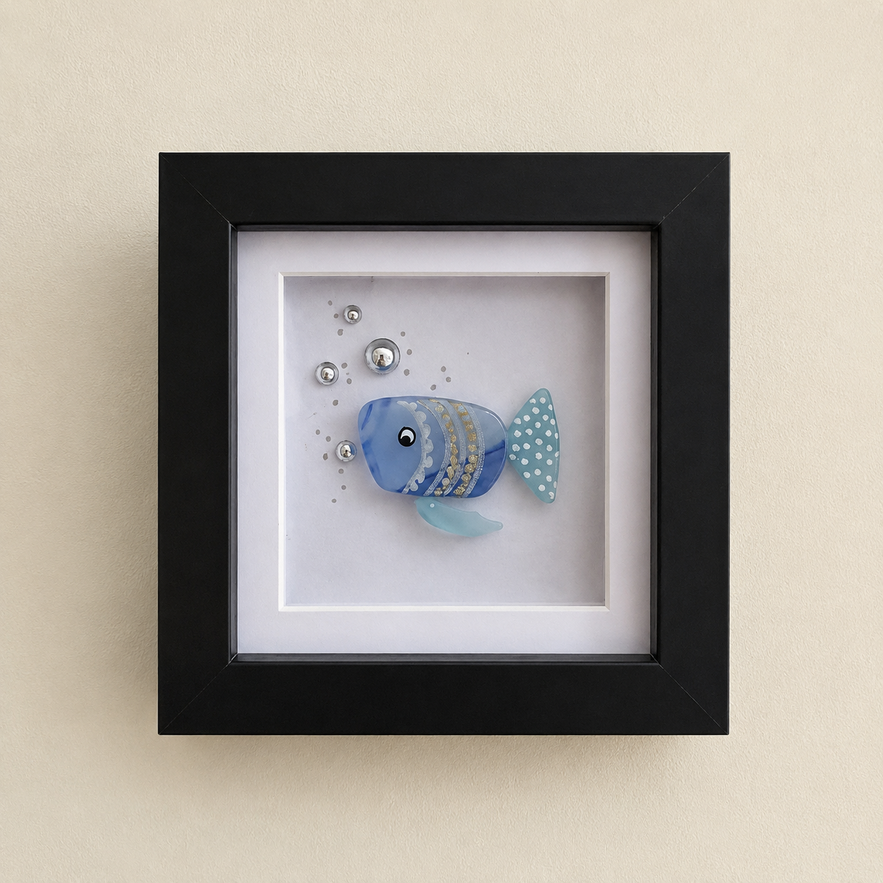 Framed decorative wall art featuring a blue fish with gold stripes and a teal tail on a white background