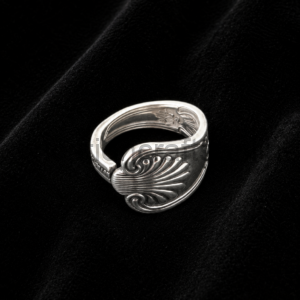 Silver open ring with a feather-like scrolling pattern displayed on black velvet backdrop.