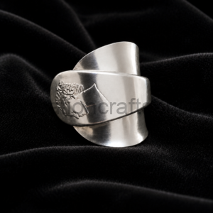 Wide silver cuff bracelet with a floral engraving resting on black velvet fabric