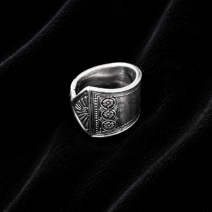 Close-up of an ornate silver ring with floral engravings on black velvet background.