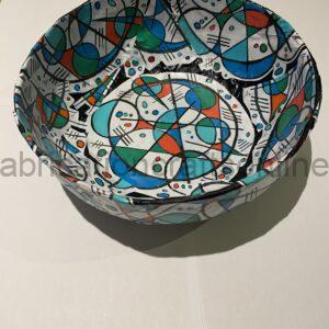 Colorful abstract-patterned bowl with blue, green, orange shapes and black lines on white surface.