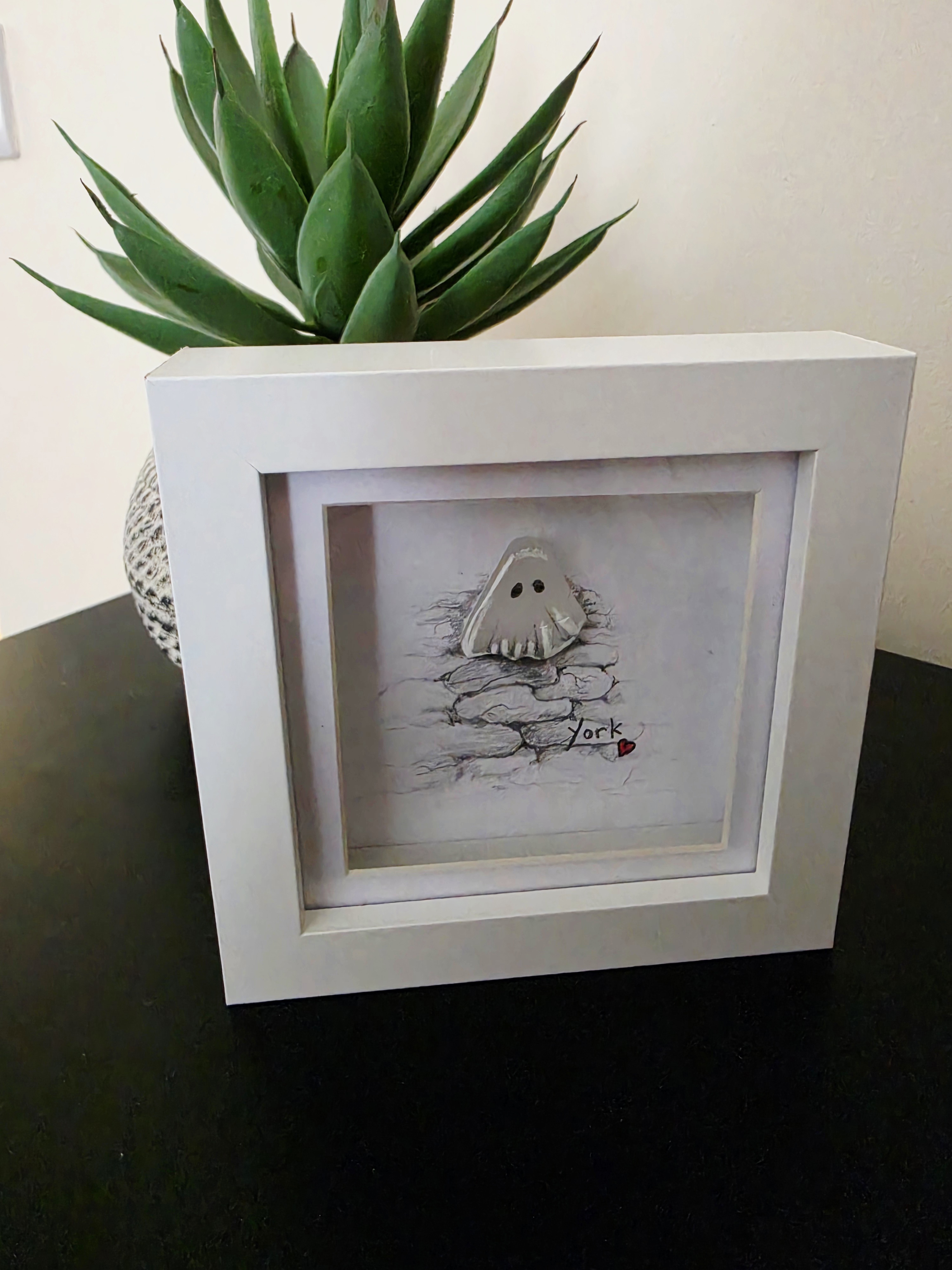 Succulent plant in a white square frame with a sketch and the word 'York' accompanied by a small red heart.