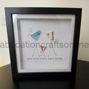 Framed drawing of a tall giraffe with pastel paper patches on its body and the caption 'and then there were three...'