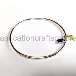 Thin silver bangle bracelet with blue and yellow gemstone end caps on a white background.