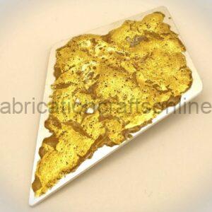 Edible gold leaf scattered over a white triangular plate, covering most of the surface