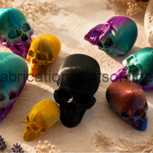 Assorted colorful skull sculptures in teal, purple, yellow, black, and copper arranged on a sandy surface.