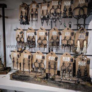 Display of multiple pairs of black metal earrings hanging on wooden boards with small white price tags in a shop display.