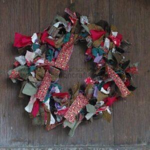 Colorful fabric-scrap wreath arranged on a dark wooden surface as a decorative craft piece