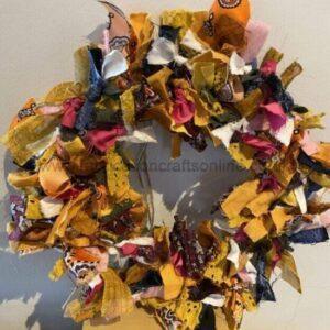 Fabric scrap wreath made of colorful torn ribbons and cloth pieces, hanging as a decorative autumn-inspired wreath.