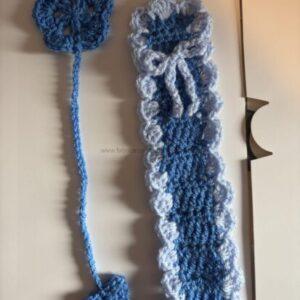Two crocheted blue pieces: a small round flower motif on the left with a tail, and a longer strip with light-blue ruffled edging on the right.