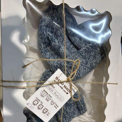 Blue-gray knitted scarf packaged in a white box with a clear window, tied with twine and a care tag visible