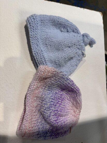Pastel gradient knitted baby sock in blue fading to pink/purple on a white surface