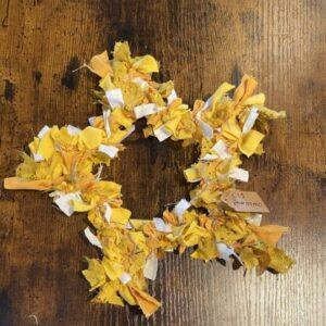 Clumps of yellow and white fabric scraps scattered on a dark wooden table surface with visible grain.