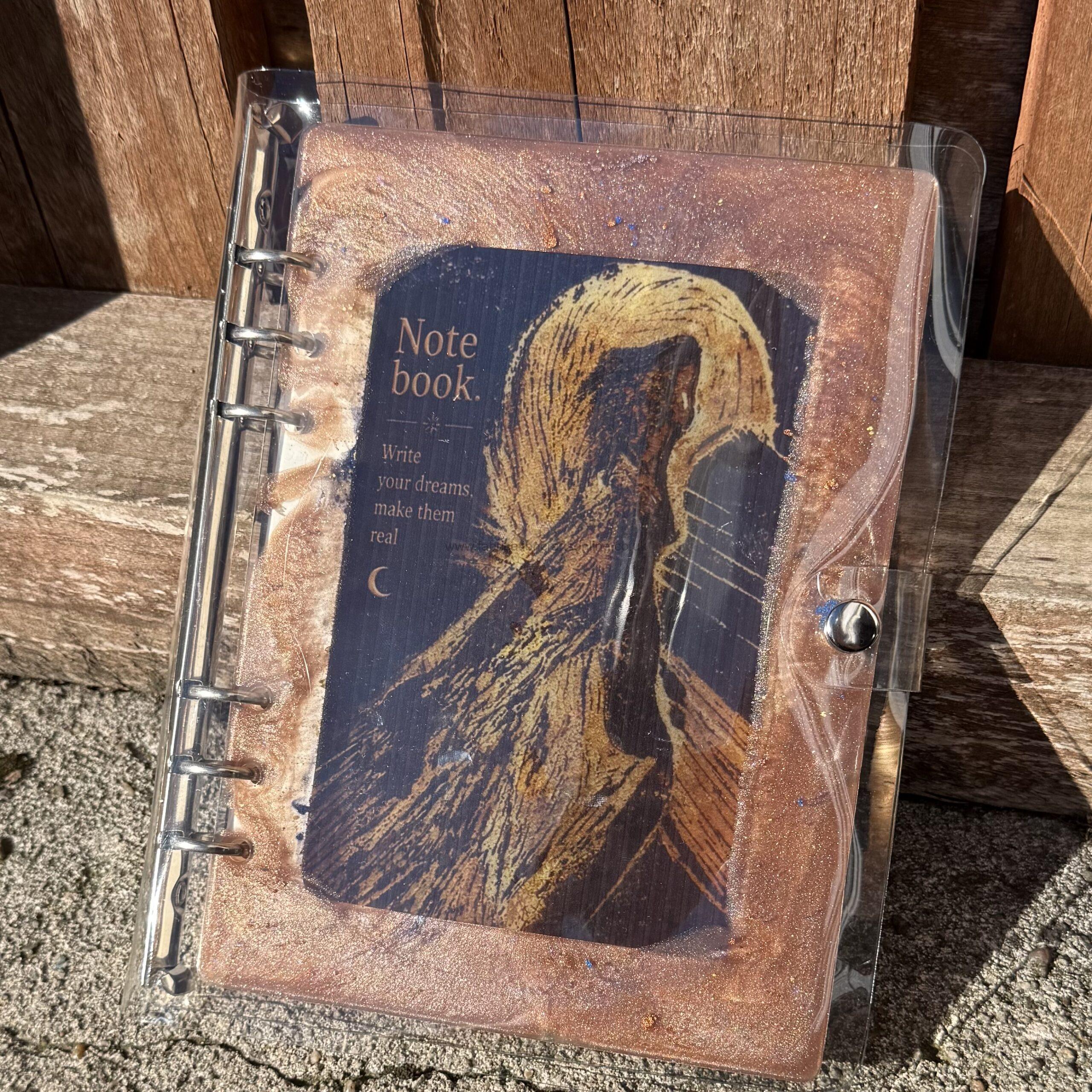 img  handmade a refillable notebook featuring an original alova artwork set within a hand poured resin cover in warm copper tones with subtle colour details
