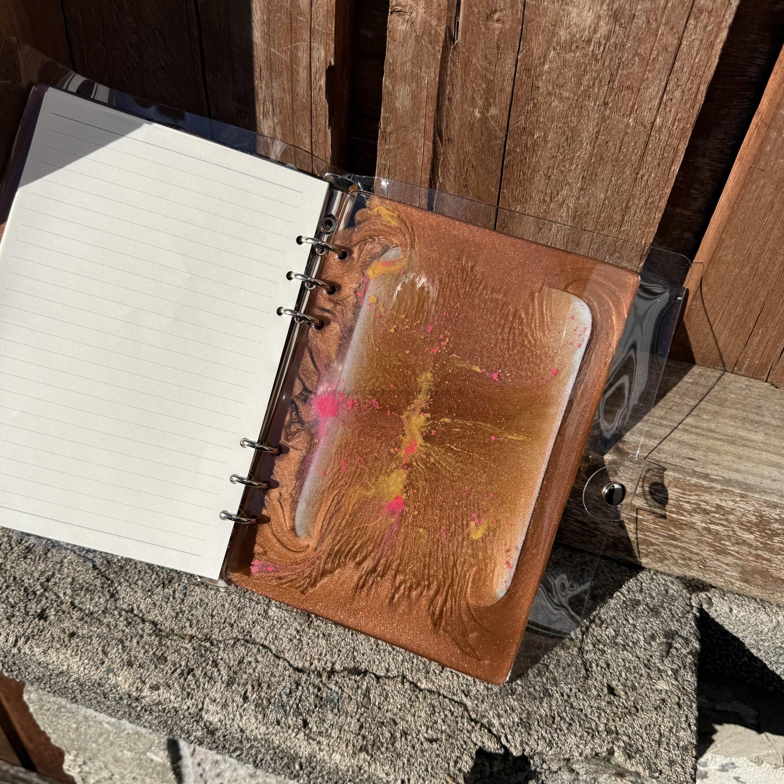 img handmade a refillable notebook featuring an original alova artwork set within a hand poured resin cover in warm copper tones with subtle colour details
