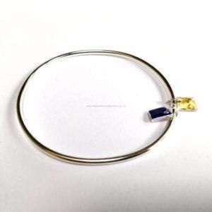 Close-up of a silver metal bracelet ring with small blue and gold charms attached on a white background.