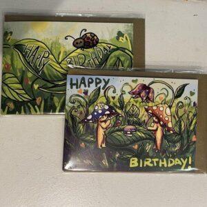 Two whimsical birthday cards with mushrooms and leaves; one says 'Happy Birthday' on a leafy green background.