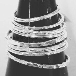 Stack of silver bangle bracelets wrapped around a black display cone.