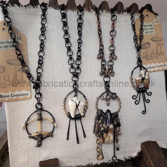 Assorted handmade metal and shell necklaces hanging on a display rack.
