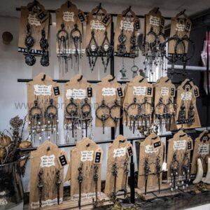 Assorted handmade dangling earrings on wooden display cards at a craft market stall. keychains or tags visible among the jewelry.