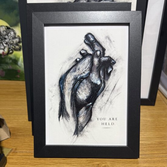 you are held a framed art print you are held is an expressive artwork exploring comfort trust and emotional connection through the gentle interaction of hands it offers a quiet reminder that we do not always have to face everything alone