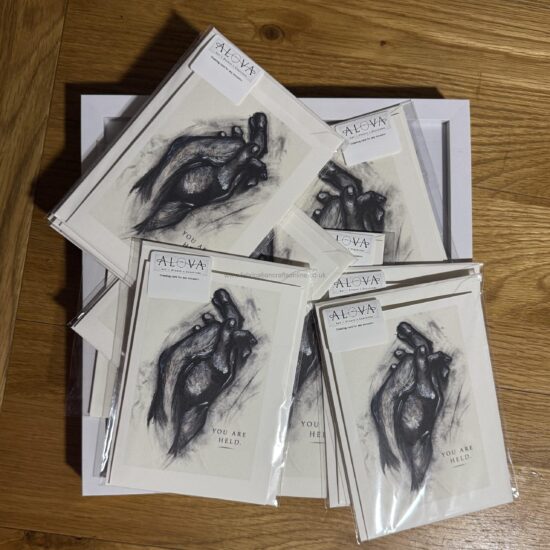 you are held a art greeting card a meaningful a greeting card featuring an expressive illustration of hands gently holding one another with the words you are held this design offers a quiet reminder of comfort connection and emotional support